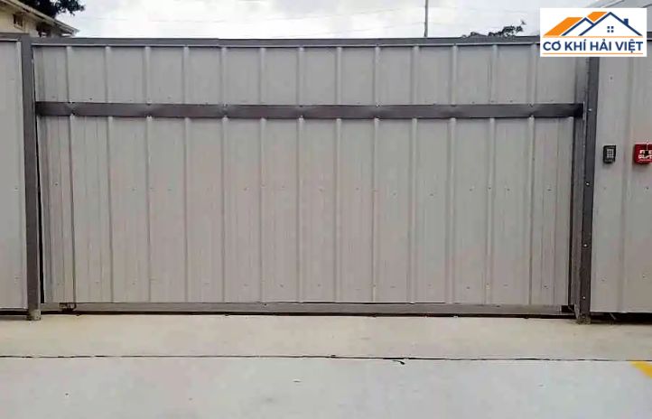 Cận cảnh mẫu cửa sắt kéo có lá, các lá tôn màu kem được lồng vào giữa các thanh U màu xám