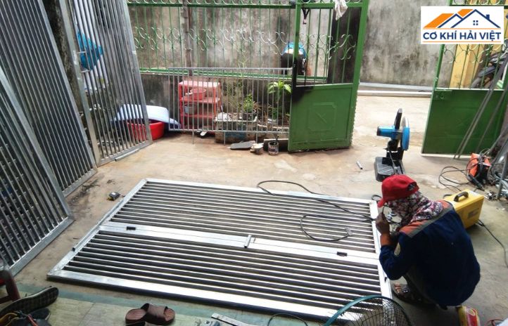 Thợ cơ khí đang lắp đặt cửa cổng sắt 2 cánh cho khách hàng