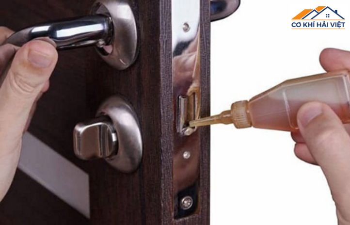 Hình ảnh một người đang dùng bình xịt bôi trơn để bảo dưỡng ổ khóa cửa sắt