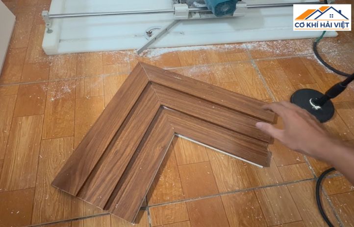 Một người thợ đang cẩn thận ghép hai thanh nẹp cửa sắt đã được cắt góc 45 độ vào góc cửa